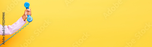 cropped view of african american woman holding blue retro phone on yellow, banner photo