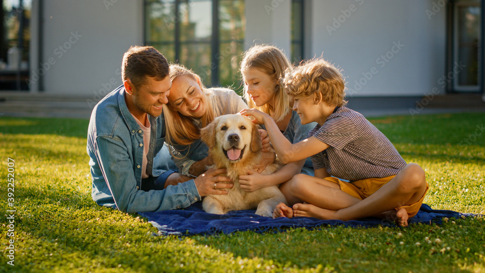 Smiling Portrait of Beautiful Family of Four Having Picnic on the Lawn, Posing with Happy Golden Retriever Dog. Idyllic Family Have Fun with Loyal Pedigree Dog Outdoors in Summer House Backyard. Smiling Portrait of Beautiful Family of Four Having Picnic on the Lawn, Posing with Happy Golden Retriever Dog. Idyllic Family Have Fun with Loyal Pedigree Dog Outdoors in Summer House Backyard.