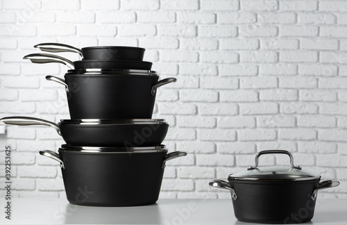 Set of cookware on table against white brick wall