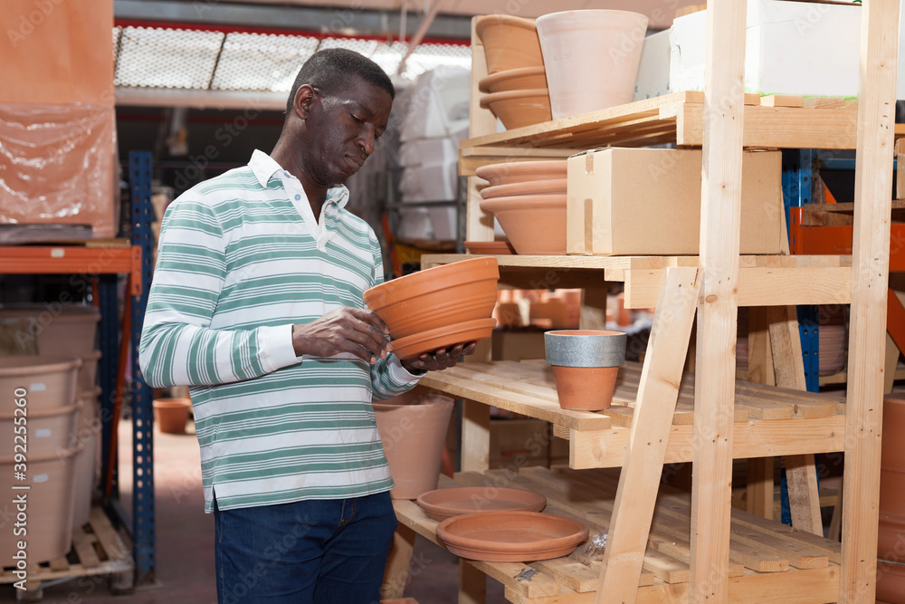 African American amateur gardener looking for flowerpots for growing plants at his smallholding