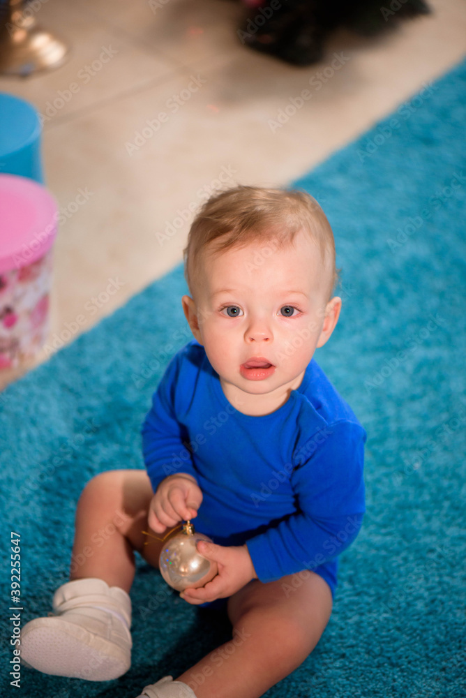 Cute boy sitting on the carpet near Christmas tree Cute boy sitting on the carpet near Christmas tree