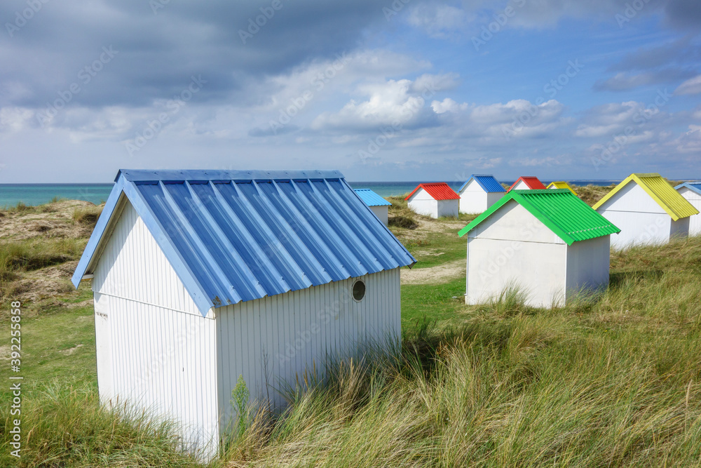 Beach huts in the dunes. Picturesque colorful wooden beach cabins at Gouville-sur-Mer, Cotentin, Normandy, France Beach huts in the dunes. Picturesque colorful wooden beach cabins at Gouville-sur-Mer, Cotentin, Normandy, France
