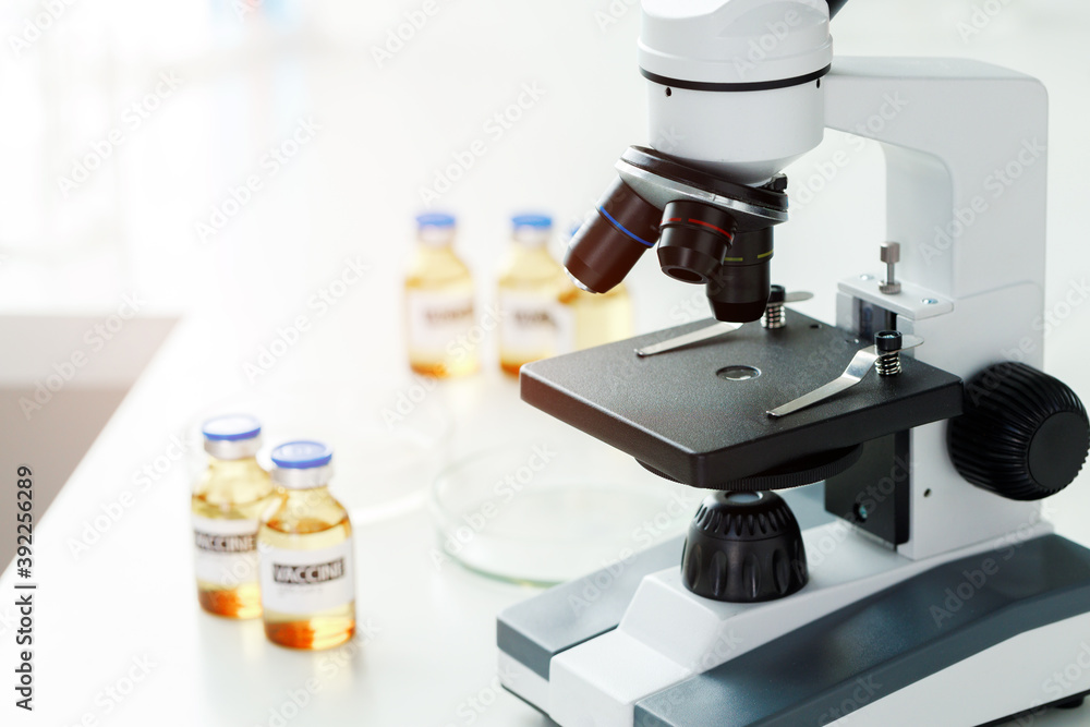 Vaccine bottles and microscope on table in a scientific lab Vaccine bottles and microscope on table in a scientific lab