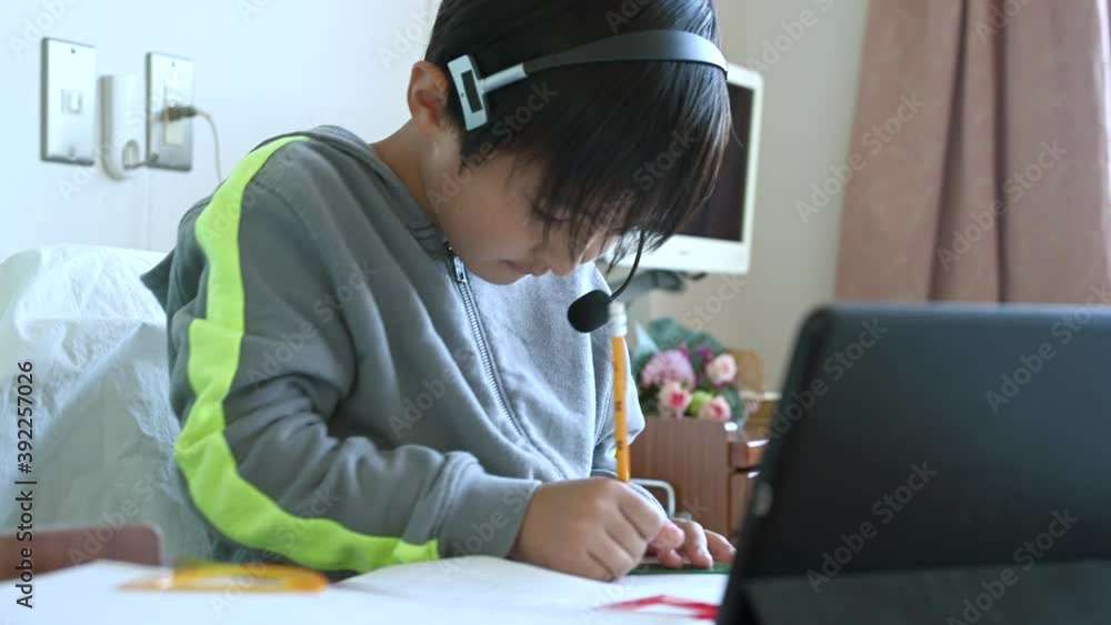 入院中の病室でオンライン授業を受ける男の子 入院中の病室でオンライン授業を受ける男の子