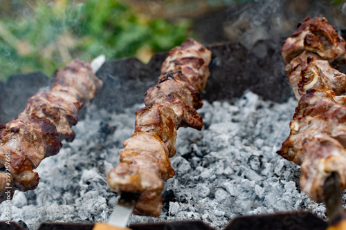 Mouth- watering skewers of pork with a toasted Golden crust and smoke flavor. Barbecue with coals in the yard in nature with cooked meat on skewers