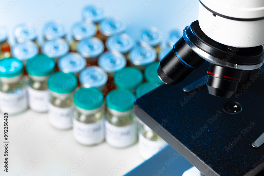 Medical vial with medication near microscope close up Medical vial with medication near microscope close up