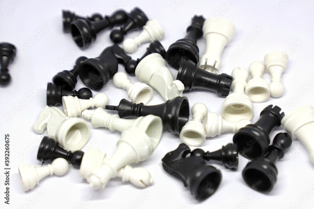 Plastic small black and white chess pieces scattered on white isolated background Plastic small black and white chess pieces scattered on white isolated background