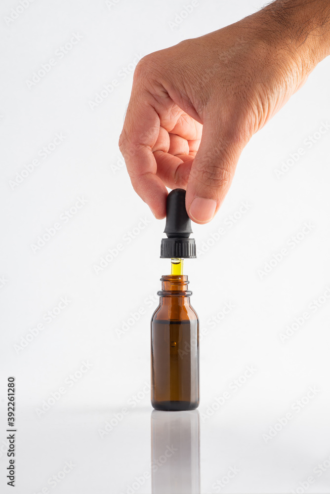 Cannabis CBD oil extracts Hemp tincture, glass bottle with dropper with hand Cannabis CBD oil extracts Hemp tincture, glass bottle with dropper with hand