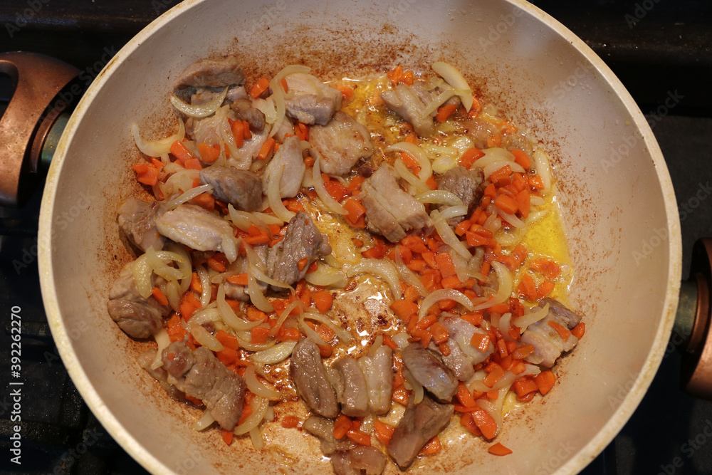 Pieces of meat, onions and carrots are fried in a pan. Selective focus. Pieces of meat, onions and carrots are fried in a pan. Selective focus.