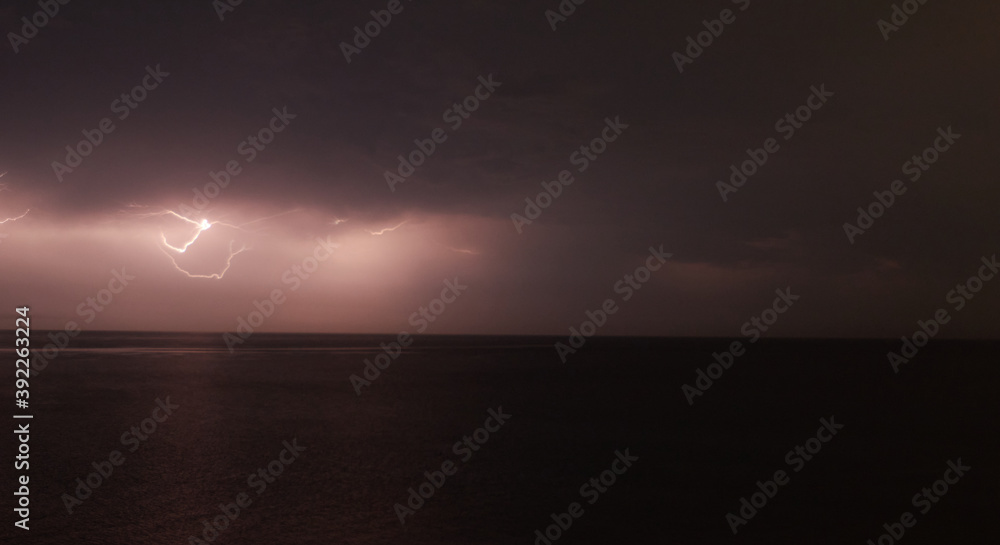 Thunderstorm with lightning over the sea at night. Lightning flashes and storm clouds Thunderstorm with lightning over the sea at night. Lightning flashes and storm clouds