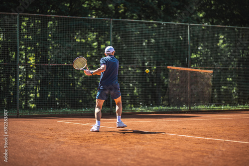 Active senior Caucasian man in sportswear playing tennis, hits a backhand groundstroke © TheSupporter
