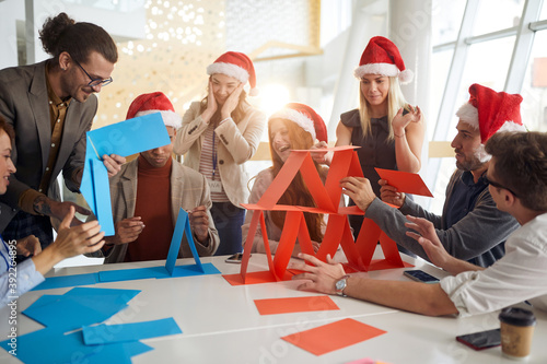 colleagues building card towers at work in the office for christmas, playing