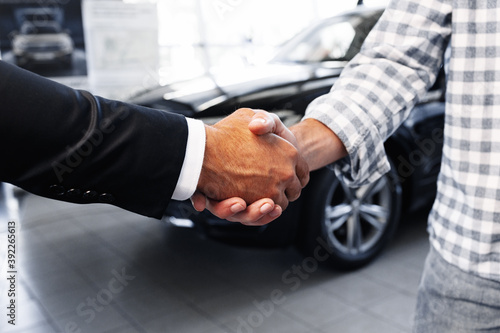 Customer shaking hands with professional car dealer at automobile dealership