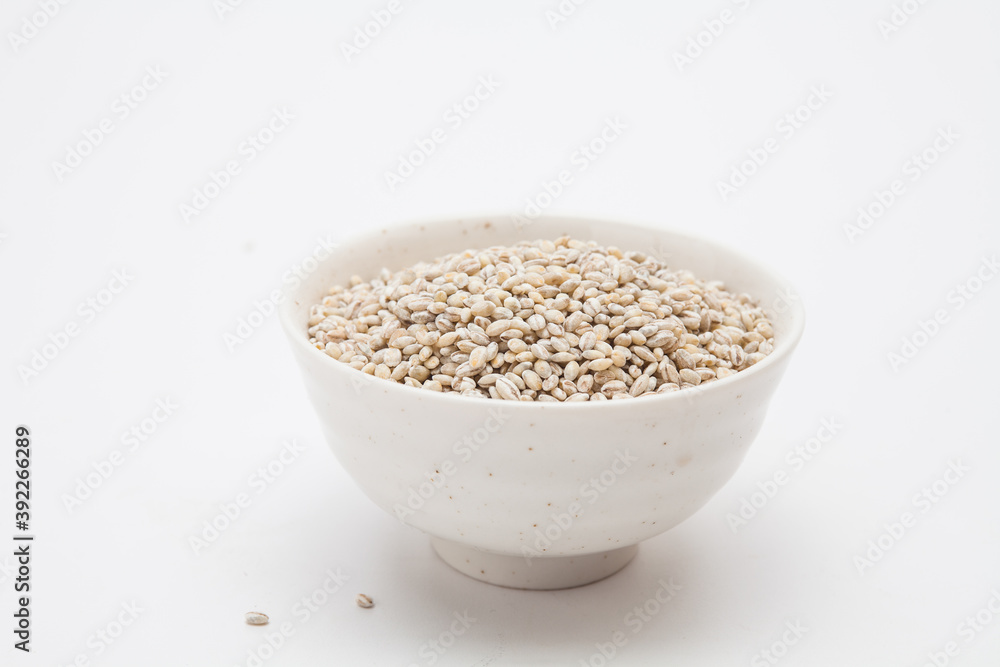 Unhulled barley in white bowl on white background Unhulled barley in white bowl on white background