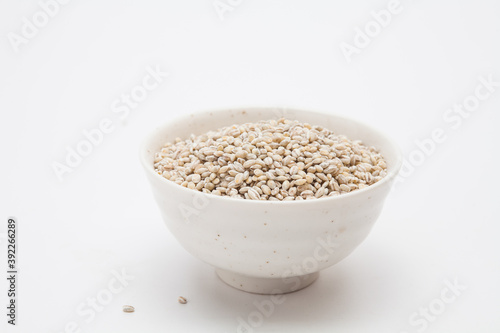 Unhulled barley in white bowl on white background 