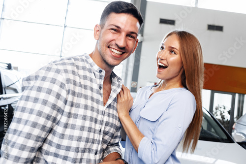 Cherrful young couple at the dealership buying a new car photo