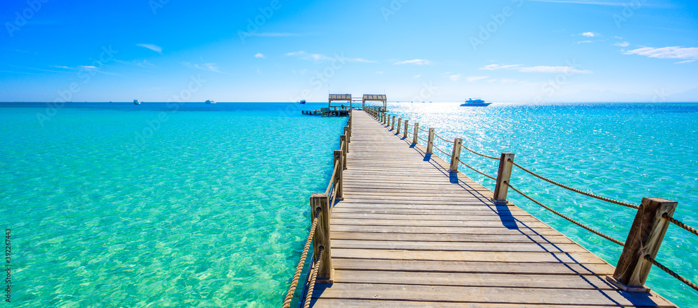 Obraz premium Wooden Pier at Orange Bay Beach with crystal clear azure water and white beach - paradise coastline of Giftun island, Mahmya, Hurghada, Red Sea, Egypt.