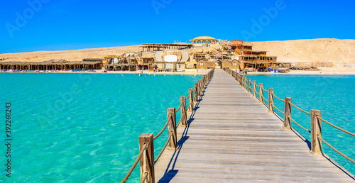 Fototapeta Naklejka Na Ścianę i Meble -  Wooden Pier at Orange Bay Beach with crystal clear azure water and white beach - paradise coastline of Giftun island, Mahmya, Hurghada, Red Sea, Egypt.