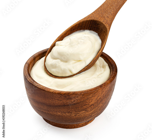 Sour cream in wooden spoon isolated on white background