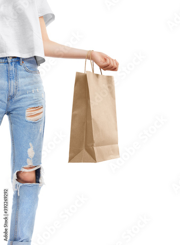 Young stylish girl figure in blue jeans with paper bag for shopping happy after buying. Shopping sale concept, isolated on white background. © LoopAll