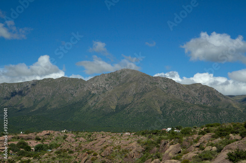 Beautiful view of popular landmark Uritorco hill, valley and green forest under a deep blue sky with clouds in Capilla del Monte, Cordoba, Argentina. photo