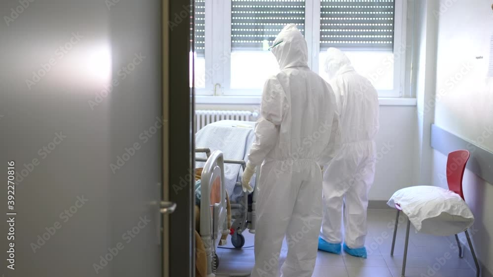 Nurses bring a bed with a newly admissed Coronavirus patient inside a room. Nurses bring a bed with a newly admissed Coronavirus patient inside a room.