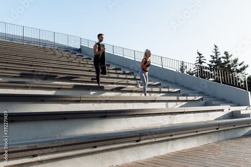 We work on the stairs. Sportive young couple in sportswear running together on stairs, outdoors