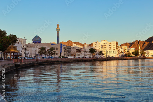 A scenic view of Muscat Corniche with the minaret of a mosque forming a beautiful reflection in the water.