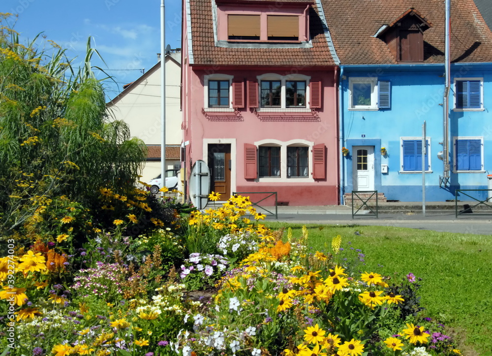 Ville de Sarreguemines, maisons et leurs façades colorées en centre ville, massif de fleurs jaunes en premier plan, département de la Moselle, France