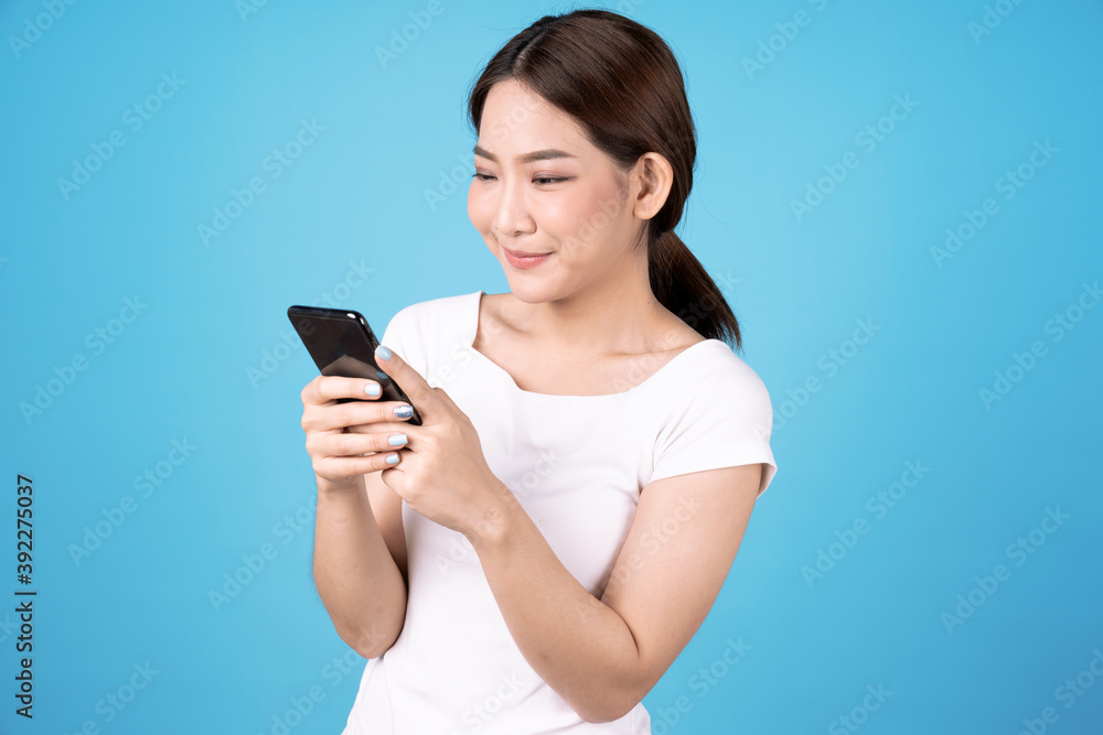 Asian woman holding a smartphone in hand, Isolated on a blue background. Asian woman holding a smartphone in hand, Isolated on a blue background.