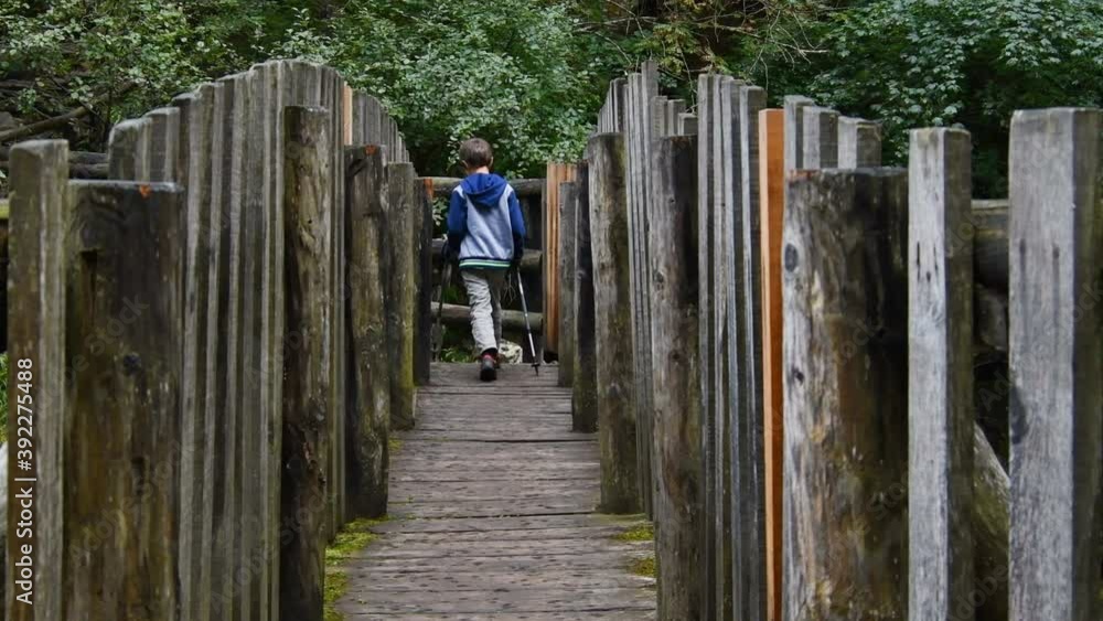Child with hiking rackets in hand as he walks on a small wooden bridge in the mountains – Real time 4K Child with hiking rackets in hand as he walks on a small wooden bridge in the mountains – Real time 4K