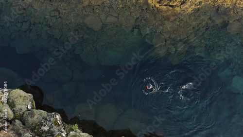 Aerial: Snorkeler swimming in Silfra popular diving / snorkeling fissure in Iceland between Eurasian and North American tectonic plates Thingvellir national park Phenomenal water clarity