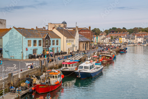 View of boats in the Old Harbour and quayside houses at dusk, Weymouth, Dorset photo