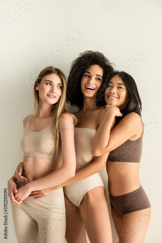 happy interracial models in underwear smiling while posing isolated on white