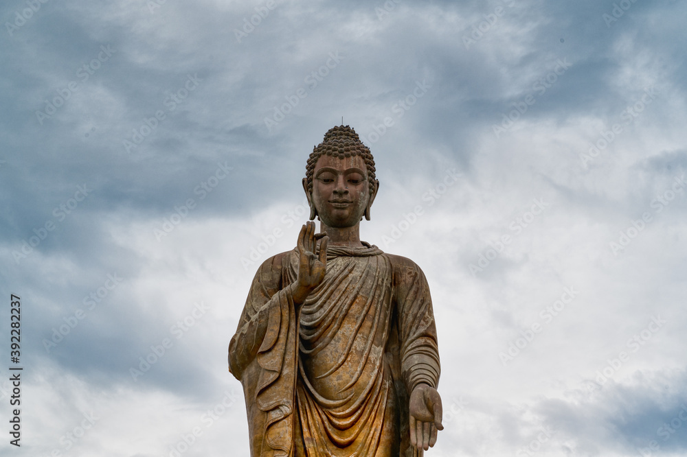 Kanchanaburi / Thailand / August 15, 2020 : Wat Thipsukhontharam Thailand’s largest standing bronze Buddha Statue. The Buddha figure is standing with the Abhaya Mudra.. Kanchanaburi / Thailand / August 15, 2020 : Wat Thipsukhontharam Thailand’s largest standing bronze Buddha Statue. The Buddha figure is standing with the Abhaya Mudra..