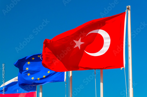 waving flags of Turkey, the European Union and Russia against the blue sky