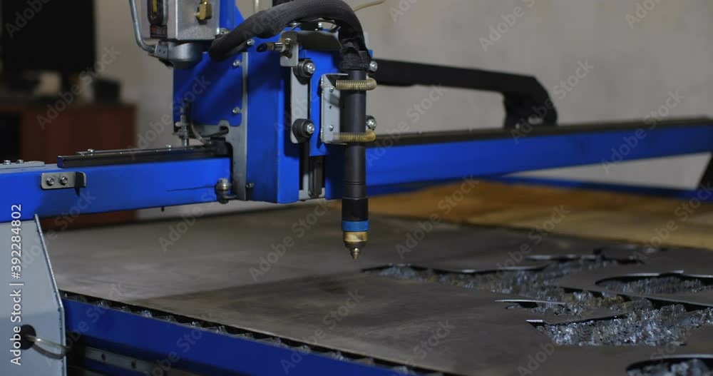 Work in the for the manufacture of tin products. A cnc plasma machine cutting a hole in