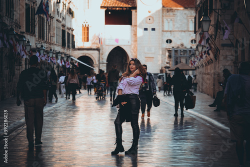 Dubrovnik Croatia November 2020 Brunette standing in the middle of the Stradun street in the old town of Dubrovnik, posing as several people walk by. Tourists walking in autumn during covid season photo