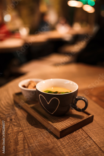 Serving cream soup in a cup with a cup of rusks on a wooden tray