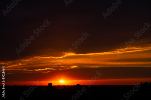 Heavy cloudy sky at sunset. Orange line of light between black clouds. A landscape of beautiful nature
