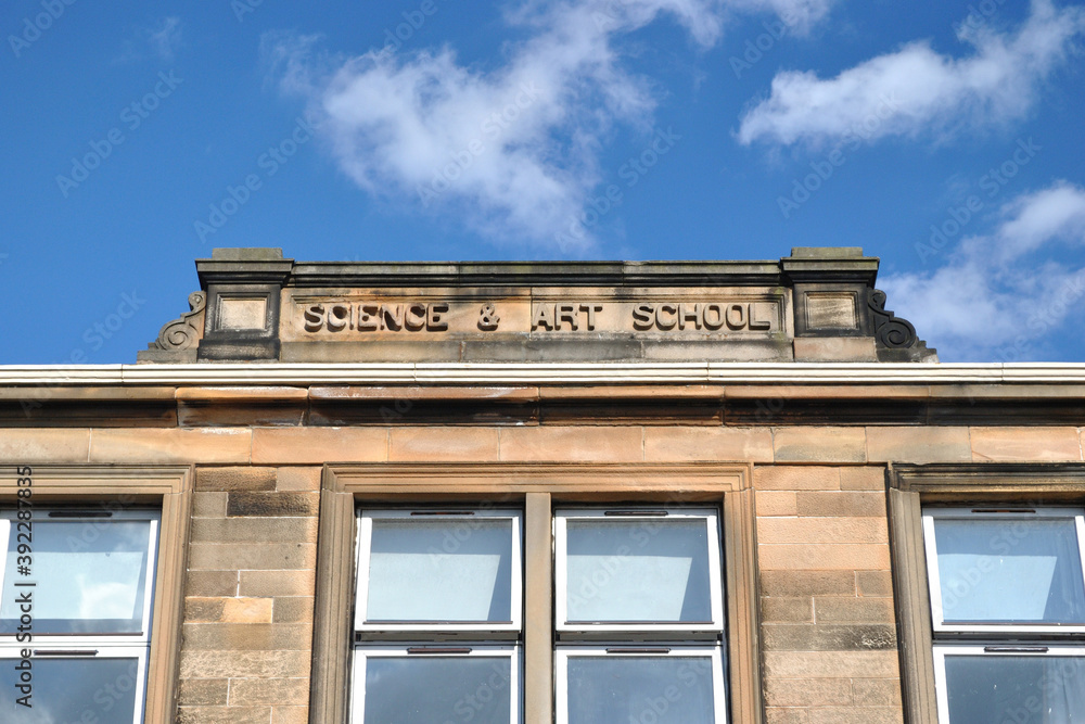Roof Line & Windows of Old Stone School Building against Blue Sky 