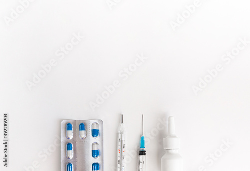 Flat lay with a set of medicines, thermometer, pills. Treating flu and colds. Top view of medicines on white background, copy space