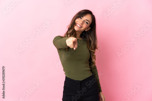 Young caucasian woman isolated on pink background pointing front with happy expression © luismolinero