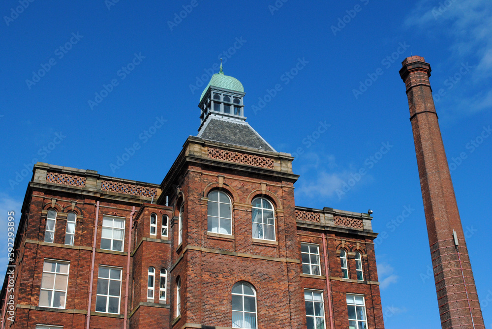 Old Victorian Mill Building & Tall Industrial Chimney against Blue Sky 