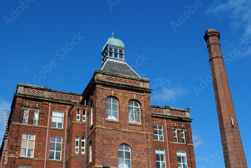 Old Victorian Mill Building & Tall Industrial Chimney against Blue Sky 