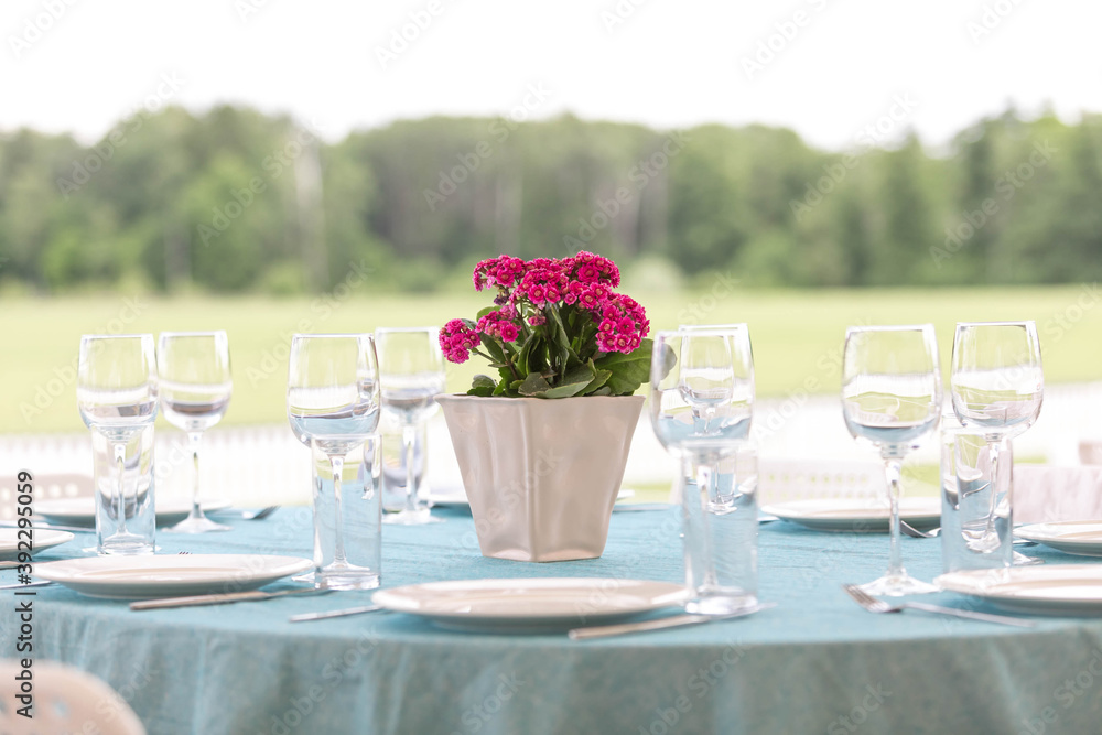 Served tables in white and blue tones standing on the street. Decorated with red flowers
