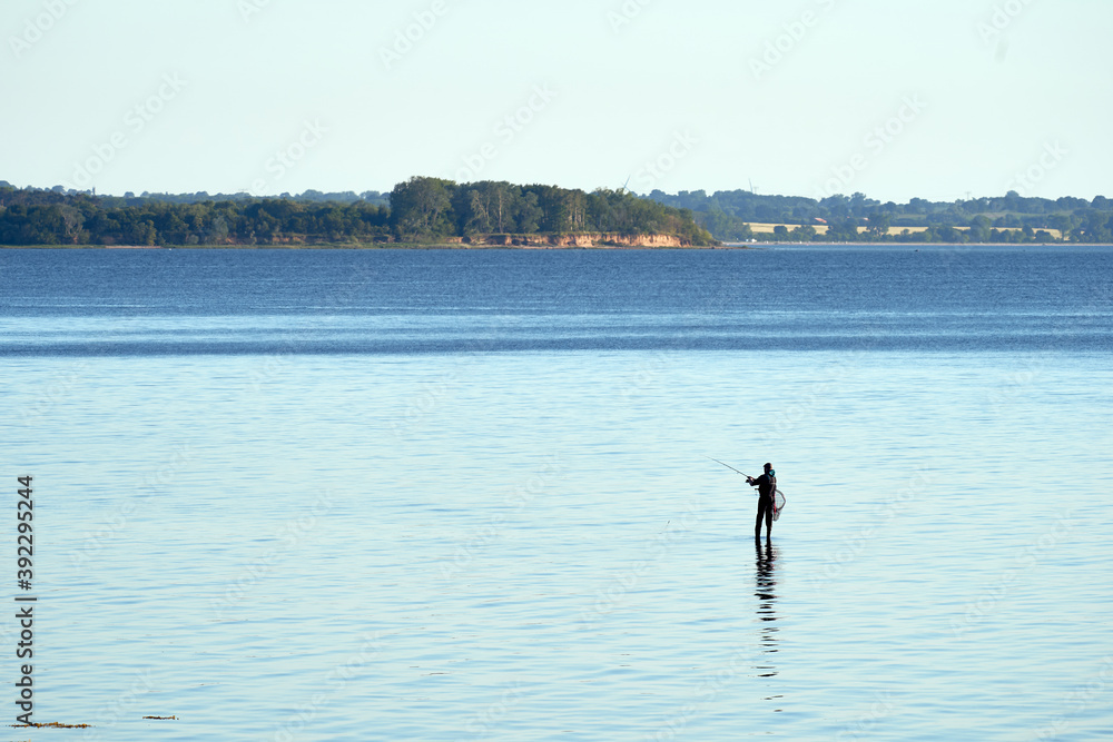 Silhouette Of A Fisherman With A Fishing Pole in the Sea