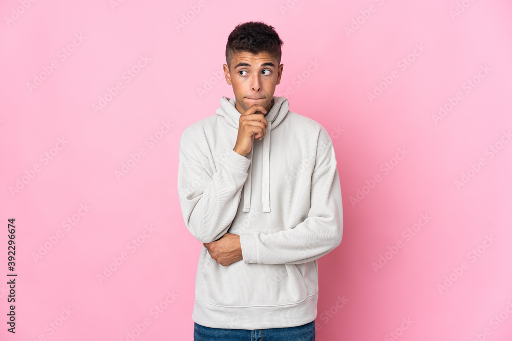 Young Brazilian man isolated on pink background having doubts and thinking Young Brazilian man isolated on pink background having doubts and thinking