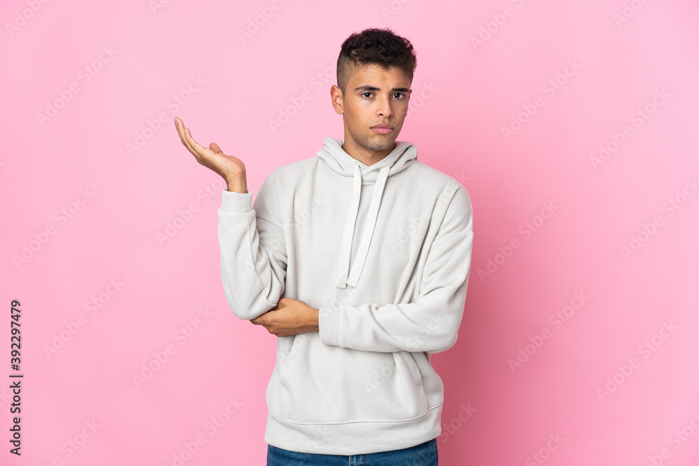 Young Brazilian man isolated on pink background having doubts Young Brazilian man isolated on pink background having doubts