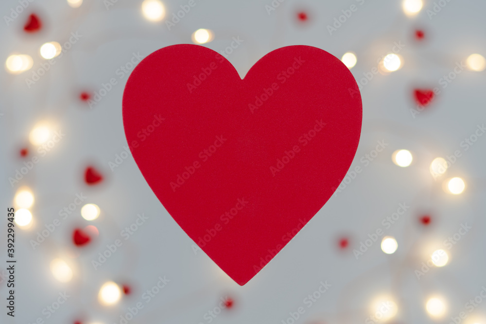 Valentines gift theme background with large red heart in foreground. Bokeh background with soft warm lights and red sparkles. Copy space available